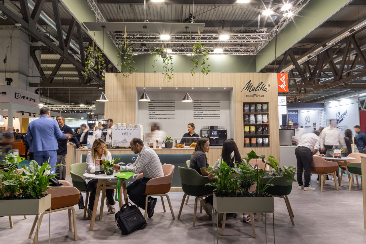 Menschen stehen und sitzen an einem Messestand