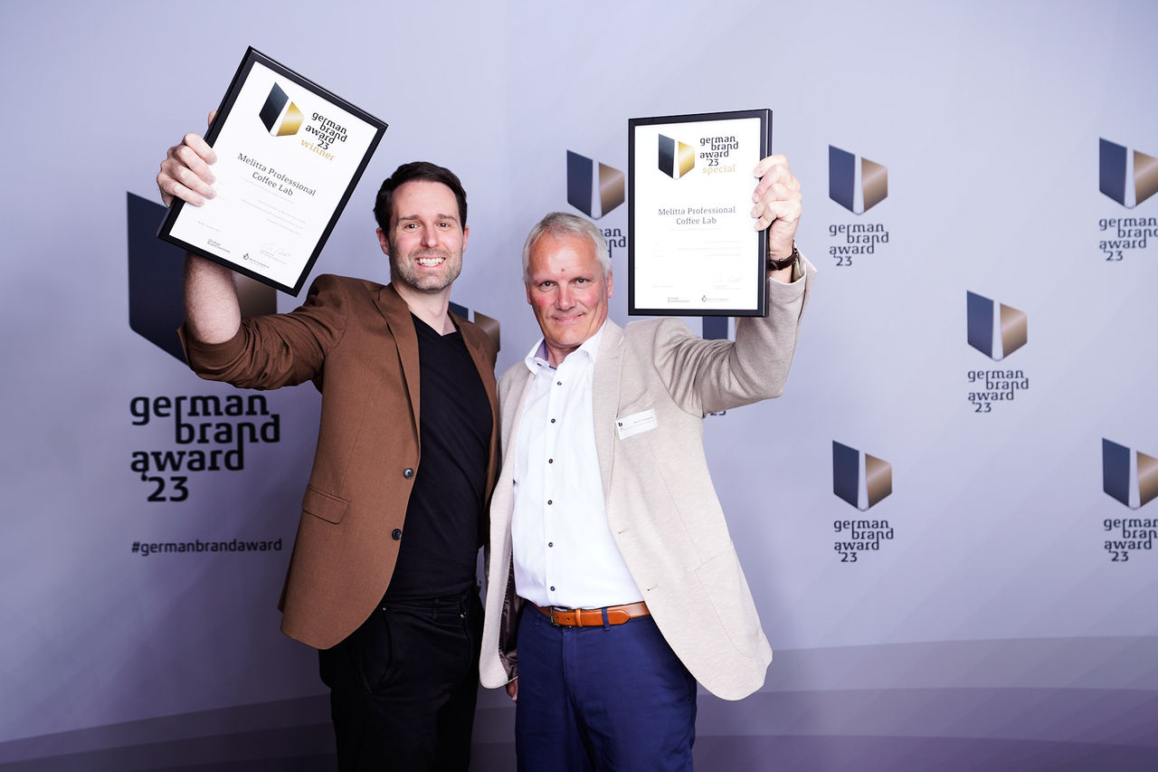 Sebastian Warnsmann und Martin Linnemann von Melitta Professional zeigen die Urkunden des German Brand Awards 2023