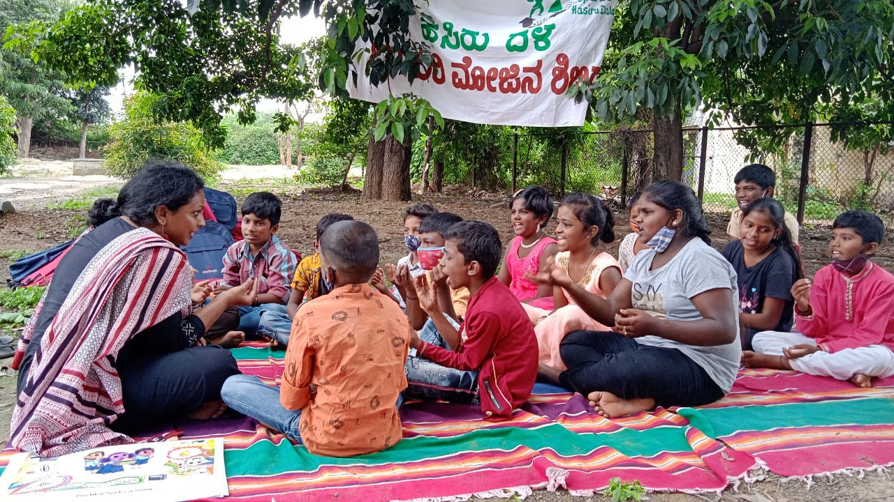 Kinder sitzen in einem indischen Park auf dem Boden